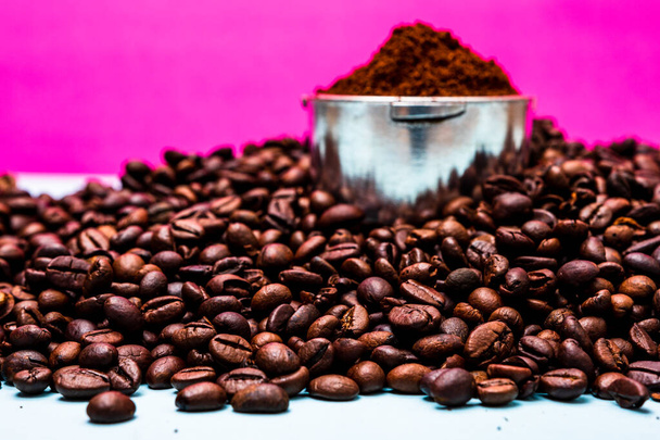 Kávová zrna a portafilter s mletou kávou ve složení na růžovém pozadí. - Fotografie, Obrázek