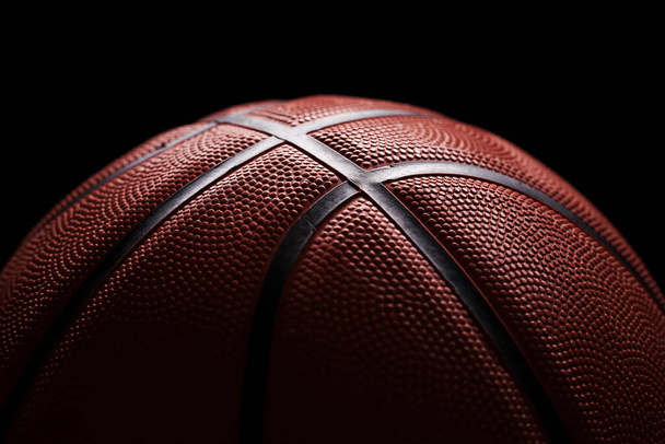 Πλευρικό φως close-up μπάλα μπάσκετ ορατή υφή και μαύρες γραμμές στο ελαστικό πορτοκαλί κάλυμμα. - Φωτογραφία, εικόνα