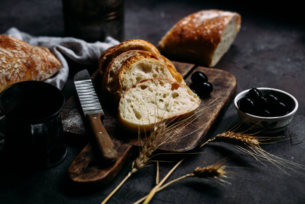 Kotitekoinen Ciabatta-leipä. Viipaloidut leipäviipaleet puulaudalla. Leipä  - Valokuva, kuva