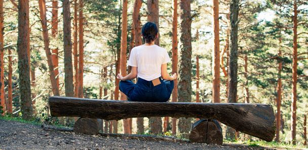 Ormanda yoga yaparken sırtüstü oturan genç bir kadın. Yatay. - Fotoğraf, Görsel