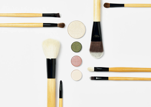 Flat lay with set of professional decorative cosmetics, makeup tools. Beauty blog, make up artist, fashion, party and shopping concept. Symmetrically arranged makeup brushes on a white background. - 写真・画像