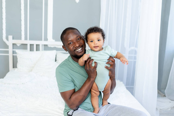 Афроамериканець з сином на руках вдома, щаслива сім'я, День батька. - Фото, зображення