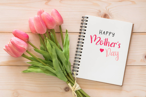 幸せな母の日お祝い挨拶上のホワイトノートブックページの背景とともにチューリップの花ギフトのためのお母さん上の木の背景 - 写真・画像