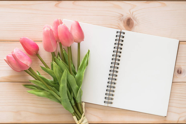 Flor de tulipán con fondo blanco de la página del libro de notas en blanco sobre fondo de madera blanca para la tarjeta de vacaciones del día de la madre y celebración de saludo estacional de primavera - Foto, Imagen