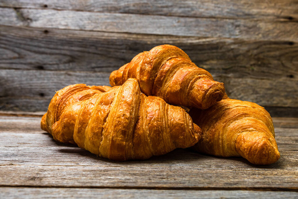 Delicious, fresh croissants isolated on wooden board. French breakfast concept. - Photo, Image