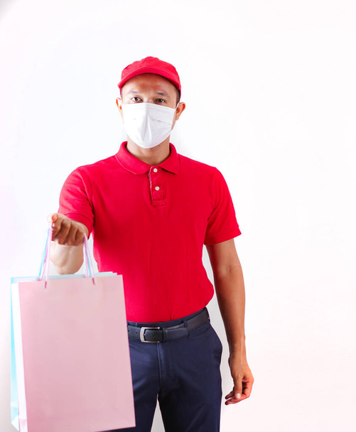 Asian Delivery man in red cap and t-shirt uniform with face mask hold empty cardboard box Service karanténa pandemic coronavirus virus covid concept. Doručit do domova - Fotografie, Obrázek
