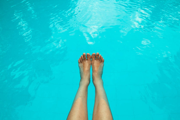Feet on the background of the blue water of the swimming pool. - Foto, Bild