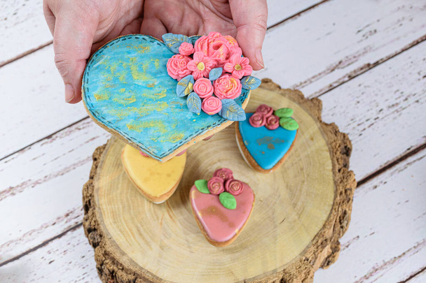 Hand holding a shortbread cookie, decorated with rolling fondant and royal icing. - Photo, Image
