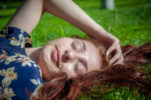 руда волохата жінка в парку, красива жінка на траві, красива жінка лежить на траві
 - Фото, зображення