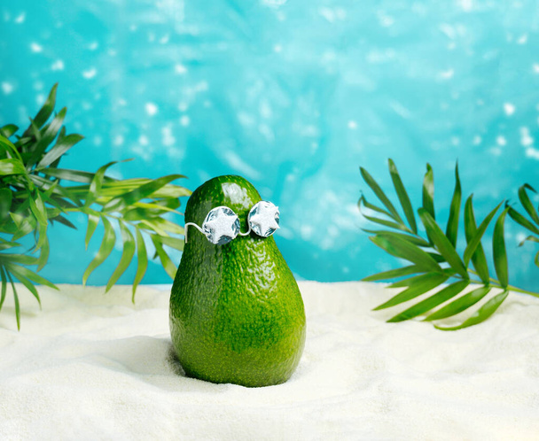 Avocado in sunglasses  relaxes  on  beach. Summer tropical minimal humor poster. - Fotografie, Obrázek