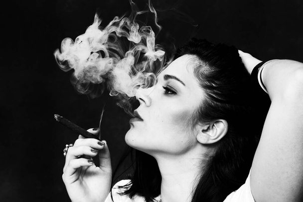 Beautiful european bossy brunette girl smoking a cigarillo like a boss in studio on isolated background. Modeling, style, fashion concept. Noir effect - Fotoğraf, Görsel