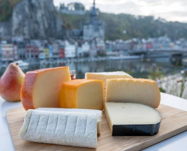 Sajtkollekció, ízletes belga apátsági sajtok barna trappista sörrel és finom fűszernövényekkel és kilátás a Maas folyóra Dinantban, Vallónia, Belgium - Fotó, kép