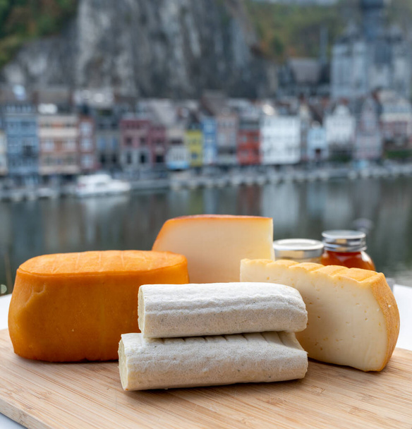 Collezione di formaggi, gustosi formaggi dell'abbazia belga realizzati con birra trappista marrone ed erbe aromatiche e vista sul fiume Maas a Dinant, Vallonia, Belgio - Foto, immagini