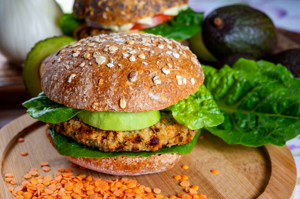 Sabrosa comida verde vegetariana saludable, hamburguesas caseras hechas de legumbres de lentejas naranjas con lechuga verde y aguacate maduro fresco - Foto, Imagen