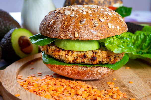 Tasty vegetarian healthy green food, homemade burgers made from orange lentils legumes with green lettuce and fresh ripe avocado - Фото, зображення
