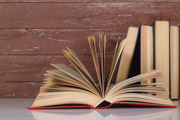 Scienza ed educazione - Aprire un libro su un gruppo di libri e sfondo in legno. Con riflessione - Foto, immagini