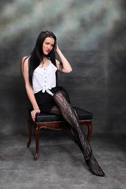 Schöne europäische Mädchen mit langen schwarzen Haaren posiert im Studio auf Leinwand Hintergrund. Stil, Trends, Modekonzept. - Foto, Bild