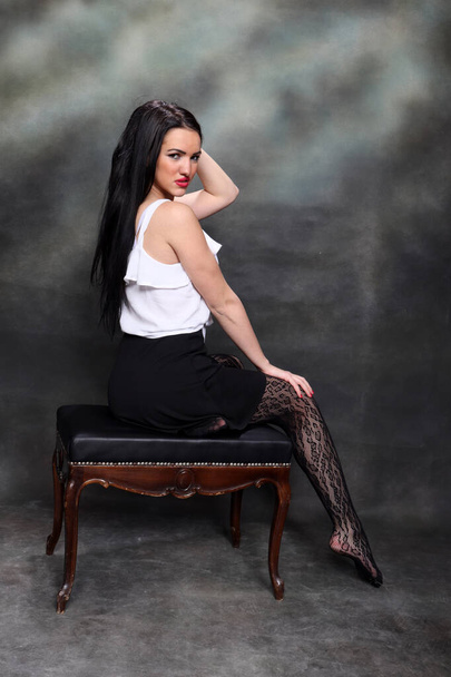 Belle fille européenne avec de longs cheveux noirs posant en studio sur fond de toile. Style, tendances, concept de mode. - Photo, image