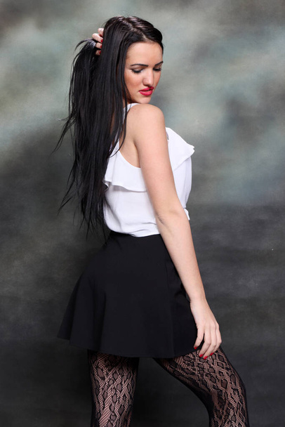 Девушка с длинными черными волосами позирует в студии на каноническом фоне. Стиль, тенденции, концепция моды. - Фото, изображение