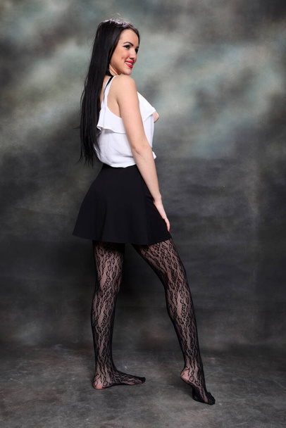 Kaunis eurooppalainen tyttö pitkät mustat hiukset poseeraa studiossa kankaalle tausta. Tyyli, trendit, muoti käsite. - Valokuva, kuva
