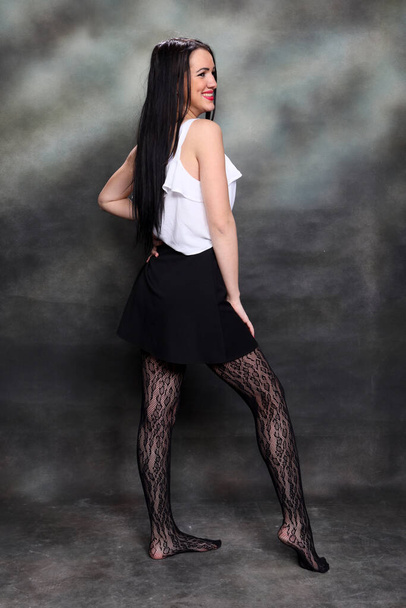 Bella ragazza europea con lunghi capelli neri in posa in studio su sfondo tela. Stile, tendenze, concetto di moda. - Foto, immagini