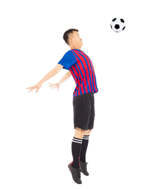Jovem jogador de futebol pulando para parar bola por peito
 - Foto, Imagem