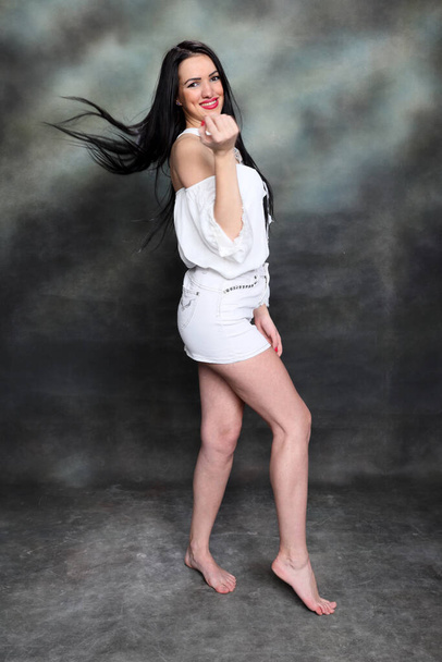 Όμορφη ευρωπαϊκή κοπέλα με μακριά μαύρα μαλλιά ποζάρουν στο στούντιο σε καμβά φόντο. Στυλ, τάσεις, έννοια της μόδας. - Φωτογραφία, εικόνα