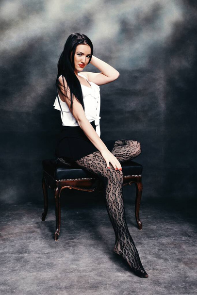 Όμορφη ευρωπαϊκή κοπέλα με μακριά μαύρα μαλλιά ποζάρουν στο στούντιο σε καμβά φόντο. Στυλ, τάσεις, έννοια της μόδας. - Φωτογραφία, εικόνα