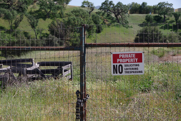 Rosso bianco nero segno su un cancello recinzione rurale dicendo PROPRIETÀ PRIVATA NO SOLICITING NO LOITERING NO TRESPASSING - Foto, immagini