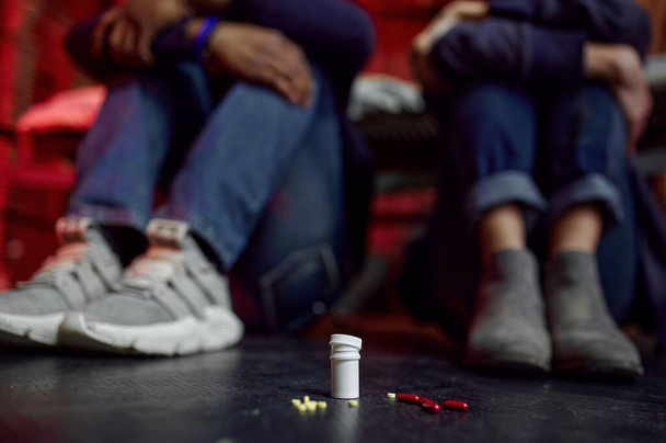Наркомани, що сидять на підлозі в дені, грандж-місце інтер'єрів на фоні, залежні від таблеток. Проблема наркоманії, вічна депресія незграбних людей
 - Фото, зображення