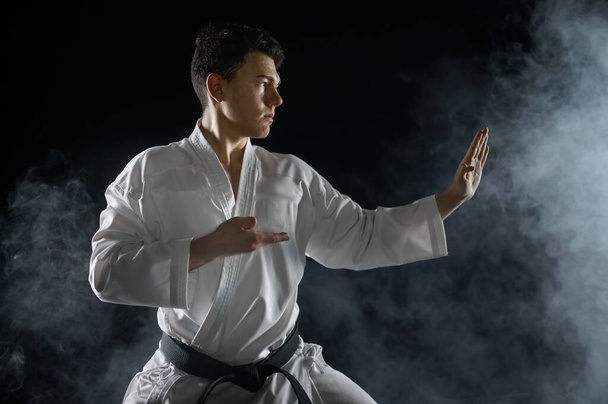 Lutador de karaté masculino em quimono branco, postura de combate, fundo escuro. Homem no treino de karaté, artes marciais, competição de luta - Foto, Imagem