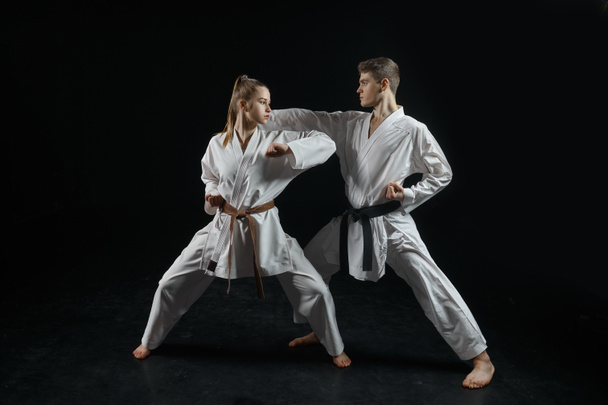 Žena karate bojovnice na tréninku s mistrem, bílé kimono, tmavé zakouřené pozadí. Karateka na cvičení, bojová umění, boj - Fotografie, Obrázek