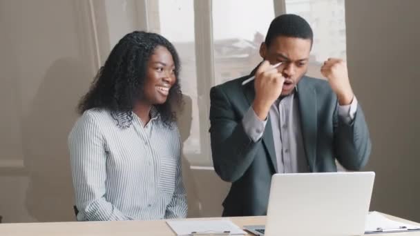 Happy excited Young african american office workers receive special commercial offer, fantastic news, opportunity. Candid emotions couple celebrate success in business or personal achievement. - Footage, Video
