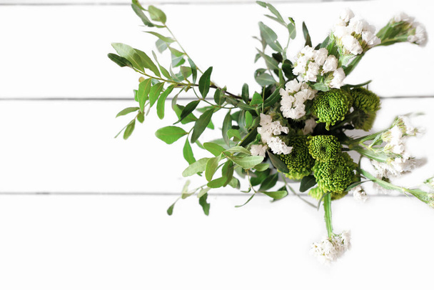 bouquet de fleurs vertes sur une table en bois blanc. vue de dessus. fleurs fraîches d'été et feuilles avec espace de copie. contenu blogueur. Bonjour ou concept de salutation, bouquet de mariage rustique. - Photo, image