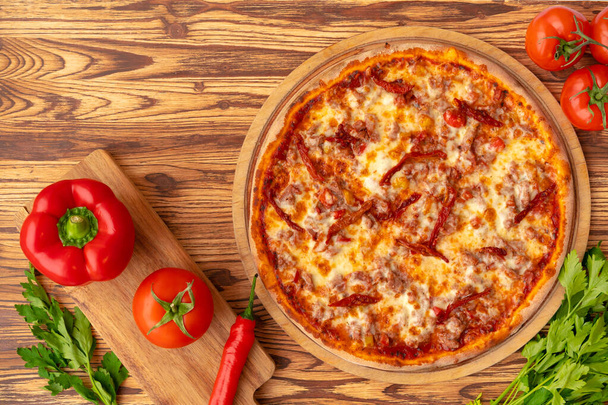 Top view of freshly baked pizza on wooden background - Zdjęcie, obraz