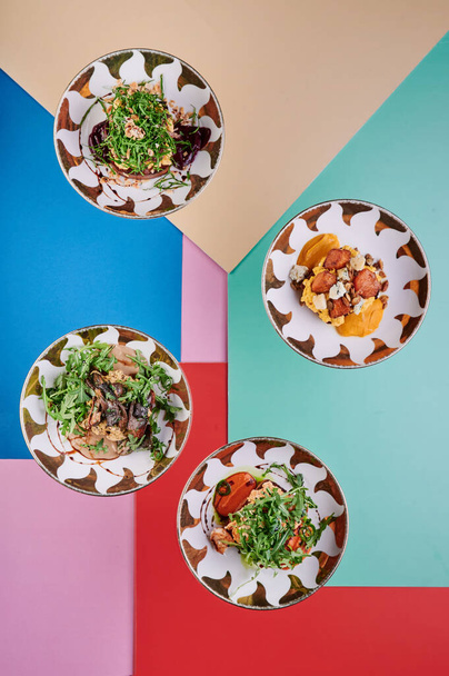 Чотири безм'ясних страви на кольоровому фоні. Вегетаріанські салати на красивих тарілках. Краєвид. Серія фотографій для меню. Макап - Фото, зображення