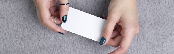 Manicured womans hands holding business card on grey furry background - Valokuva, kuva