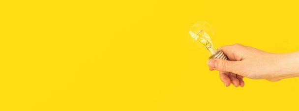 Banner mão segurando lâmpada no fundo amarelo, nova ideia conceito fundo com espaço de cópia - Foto, Imagem