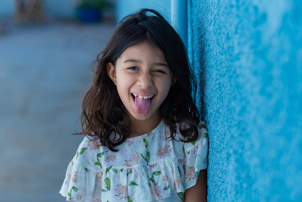 Ein fröhliches Mädchen mit ausgestreckter Zunge, das ein Gesicht macht. - Foto, Bild