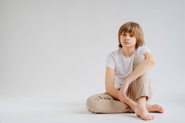 teen boy in white T-shirt pose in a photo studio. problems for teenage boys.  - Fotó, kép