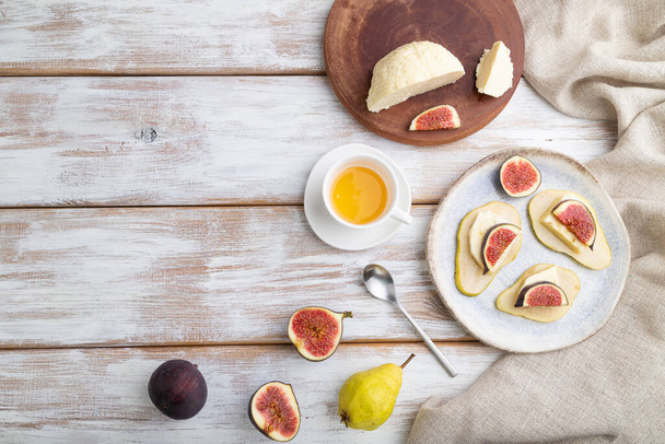 Summer appetizer with pear, cottage cheese, figs and honey on a white wooden background and linen textile. Top view, flat lay, copy space. - Foto, immagini