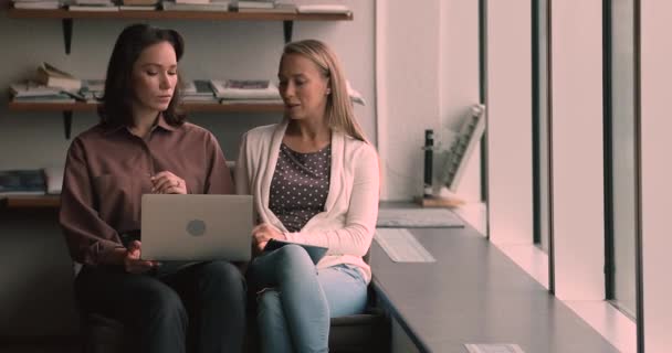 Two female colleagues meet in office lounge room with laptop - Imágenes, Vídeo