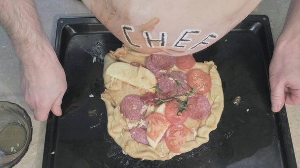 Толстяк с надписью "шеф-повар" готовит пиццу. Закрыть - Фото, изображение