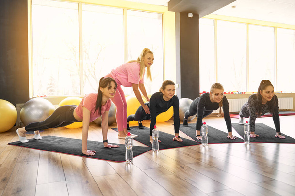 Group of young women doing plank together in gym - Foto, afbeelding