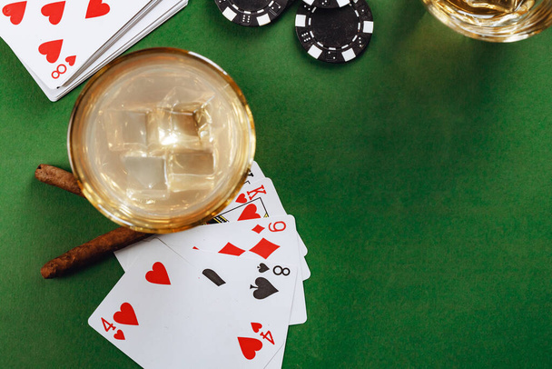 Glass of whiskey, cigar, playing cards and chips on green background - Foto, Imagem