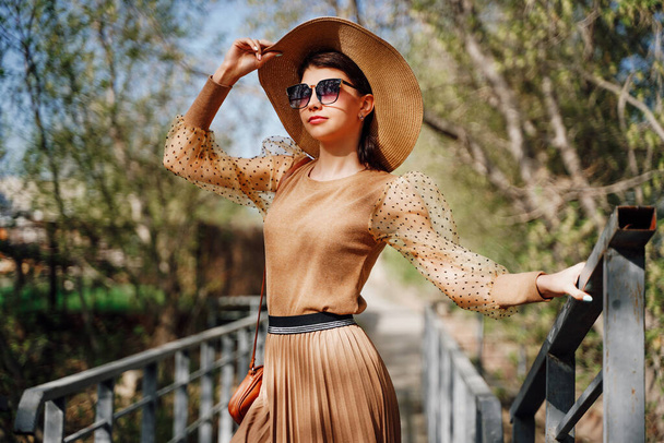 ベージュのパステルカラーの美しい若い女性は、帽子とサングラスをかけています。春と夏のためのスタイリッシュなファッショナブルなイメージ、衣類の傾向。フランス風夏顔に太陽のまぶしさ. - 写真・画像