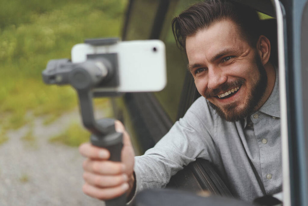 Retrato de hombre exitoso grabación vlog en el teléfono inteligente con steadycam - Foto, imagen