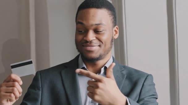 Portré boldog mosolygós jóképű fiatal afro-amerikai bank alkalmazott üzletember kezében hitelkártya mutatja hüvelykujj-up mutatja előnyeit bankkártya. Az e-banki alkalmazás szolgáltatási koncepciója.  - Felvétel, videó