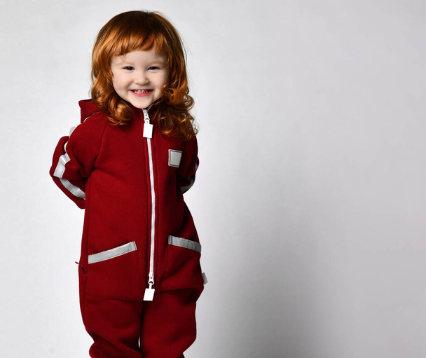 red-haired preschooler girl wearing warm tracksuit studio portrait - Fotoğraf, Görsel