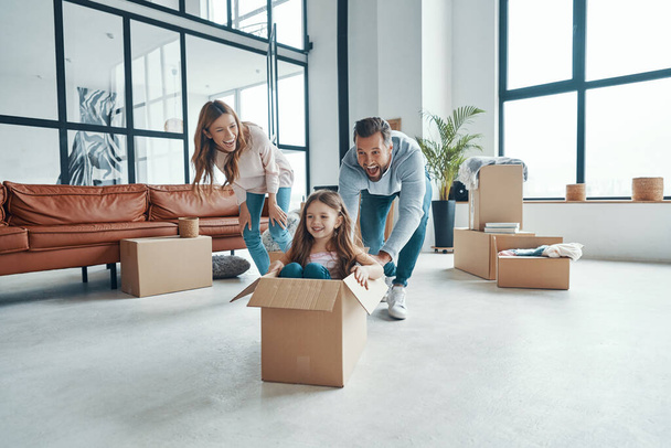 Happy young family smiling and unboxing their stuff while moving into a new apartment - Foto, Imagem